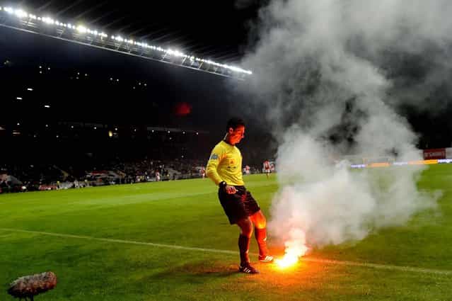 Referee Carlos Xistra tries to extinguish a flare thrown by FC Porto's fans at the game with Sporting Braga during their Portuguese League soccer match at the Municipal Stadium in Braga, November 25, 2012, Portugal. Porto won 2–0. (Photo by Paulo Duarte/Associated Press)