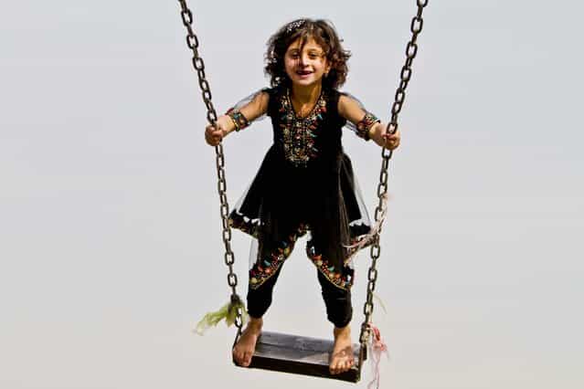 A girl enjoys a swing in an amusement park in Jalalabad, Afghanistan, November 12, 2012. (Photo by Rahmat Gul/Assoiciated Press)
