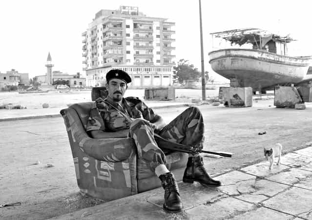 [Libyan Rebel at the Old Shipyard of Benghazi: During the Libyan revolt against Moammar Qaddafi, the city of Benghazi was liberated early on, and became the base for the rebels and the transitional governing body. Armed rebels were seen all over the place. Many of them had no previous war experience but joined the revolt willingly to get rid of the regime. This rebel, with his spick & span boots and outfit, was guarding the old shipyard]. (Photo and comment by Mohannad Khatib/National Geographic Photo Contest via The Atlantic)
