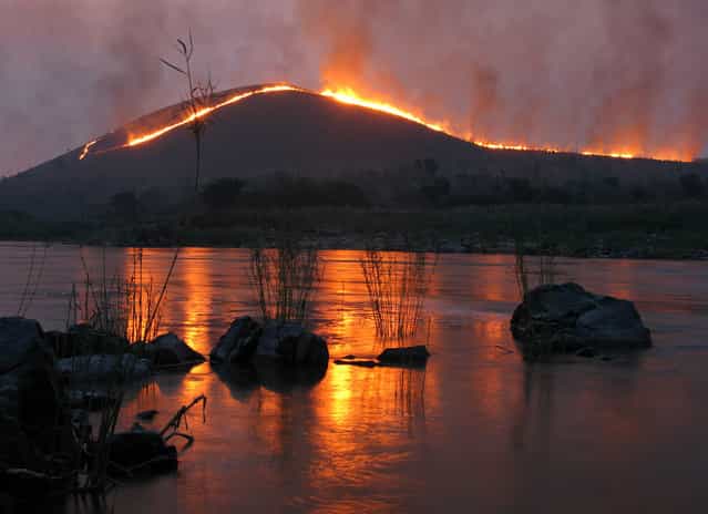 [The Congo River, deep in the Democratic Republic of Congo: Downstream from the infamous [Gates of Hell] rapids on the Congo river, this was the view from my camp during my five month canoe trip from source to sea. The grass covered hills were being burnt down for farming in the background]. (Photo and comment by Phil Harwood/National Geographic Photo Contest via The Atlantic)