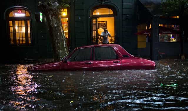 A car is submerged in floodwater in front of a home in Buenos Aires, Argentina, December 6, 2012. (Photo by Natacha Pisarenko/Associated Press)