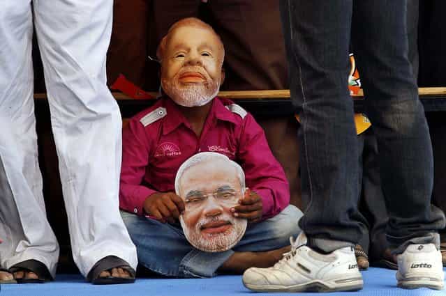 A young supporter wearing a mask of Gujarat Chief Minister Narendra Modi listens to a speech during an election campaign rally for state assembly elections at Prantij in Ahmadabad, India, December 15, 2012. The second phase of polling for the Gujarat state Assembly elections is scheduled to be held on Monday. (Photo by Ajit Solanki/Associated Press)