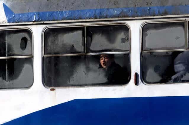 A man blows onto the frosted window of a tram in Pyongyang, North Korea, December 19, 2012. (Photo by Ng Han Guan/Associated Press)