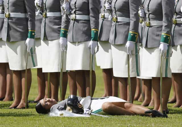 A cadet lies on the grass after collapsing during a promotion ceremony at a police school in Bogota December 7, 2012. (Photo by John Vizcaino/Reuters)