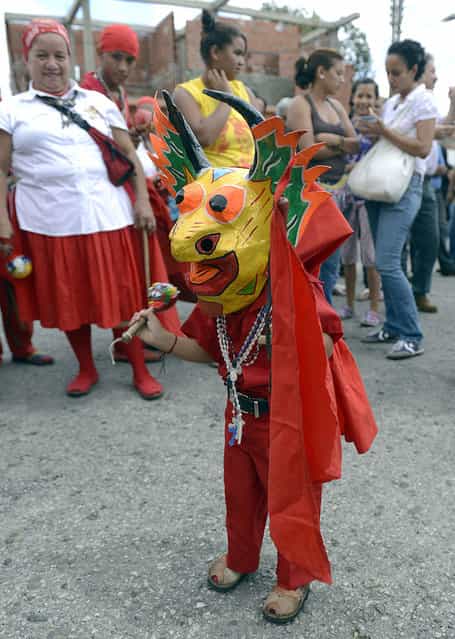 A young member of the Dancing Devils performs during a demonstration in the Venezuelan village of Yare, Miranda State, on December 7, 2012. On December 6, the UNESCO declared the Dancing Devils as an Intangible Cultural Heritage of Humanity. Every Corpus Christi day, the Dancing Devils, in colourful costumes and wearing grotesque masks, perform their ritual during the Dancing Devils of Yare folkloric festivity. (Photo by Juan Barreto/AFP Photo)