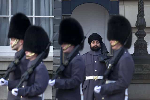 Sikh Scots Guards soldier Jatenderpal Singh Bhullar (2-R), stands on guard duty outside Buckingham Palace in central London on December 13, 2012. Jatenderpal Singh Bhullar became the first guardsman to parade outside Buckingham Palace wearing a turban instead of the bearskin. (Photo by Carl Court)
