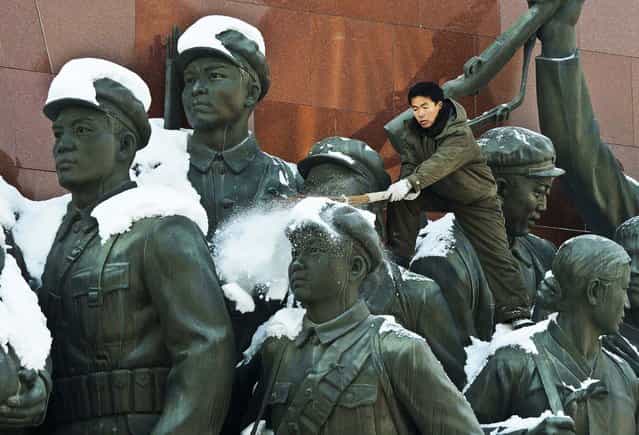 A man brushes snow from the monument of anti-Japanese revolutionary fighters on Mansu Hill in Pyongyang, North Korea, December 10, 2012. (Photo by Kyodo News)