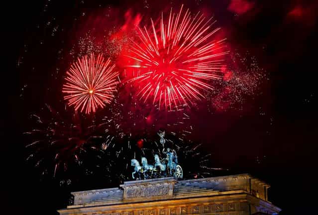 Fireworks explode in the sky above the Quadriga on the Brandenburg Gate during the New Year's celebrations in Berlin, Tuesday, Jan. 1, 2013. (Photo by Markus Schreiber/AP Photo)