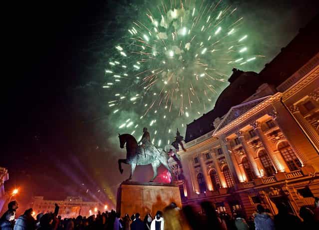 Fireworks explode above the statue of King Carol I in downtown Bucharest, Romania. (Photo by Vadim Ghirda/Associated Press)