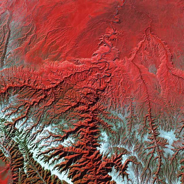 Utah’s Green River cuts across the Tavaputs Plateau (top) before entering rugged Desolation Canyon (center), which cuts southward through first the Roan and then the Book Cliffs – two long, staircase-like escarpments that run west-east from Utah into Colorado. Desolation Canyon, seen in the center of this image, was named by the famous American explorer John Wesley Powell, for its intimidating, rugged terrain. Eighty miles long and nearly as deep as the Grand Canyon, it is one of the largest unprotected wilderness areas in the West. This image shows the Green River cutting a path through the vegetation of the Plateau. The river appears blue while the vegetation is red. Snow dusts the peaks of the Roan Cliffs, which appears light blue to white. This image was acquired by Landsat 7’s Enhanced Thematic Mapper plus (ETM+) sensor on December 31, 2000. This is a false-color composite image made using near-infrared, red, and green wavelengths. The image has also been sharpened using the sensor’s panchromatic band. (Photo by NASA/GSFC/USGS EROS Data Center)