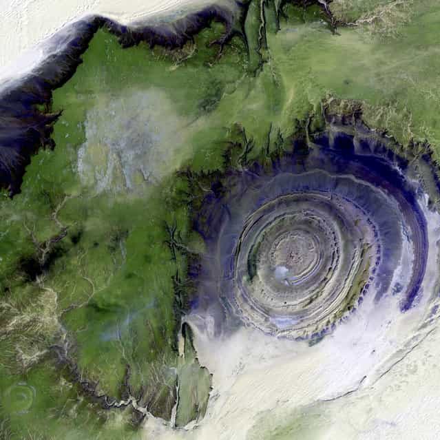 Richat Structure, Mauritania. The so-called Richat Structure is a geological formation in the Maur Adrar Desert in the African country of Mauritania. Although it resembles an impact crater, the Richat Structure formed when a volcanic dome hardened and gradually eroded, exposing the onion-like layers of rock. This image was acquired on January 11, 2001, by Landsat 7′s Enhanced Thematic Mapper plus (ETM+) sensor. This is a false-color composite image made using shortwave infrared, infrared, and green wavelengths, and has been sharpened using the sensor’s panchromatic band. (Photo by NASA/GSFC/USGS EROS Data Center)