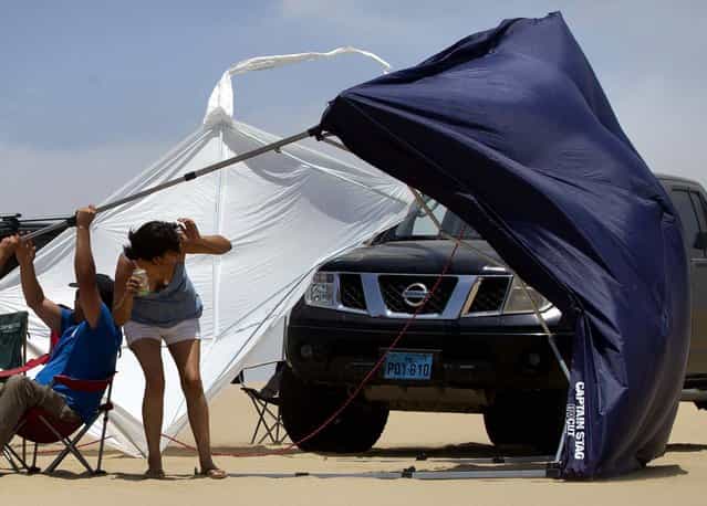 A tent is blown away by strong gusts of wind as spectators watch the 1st stage near Pisco, Peru. (Photo by Victor R. Caivano/Associated Press)
