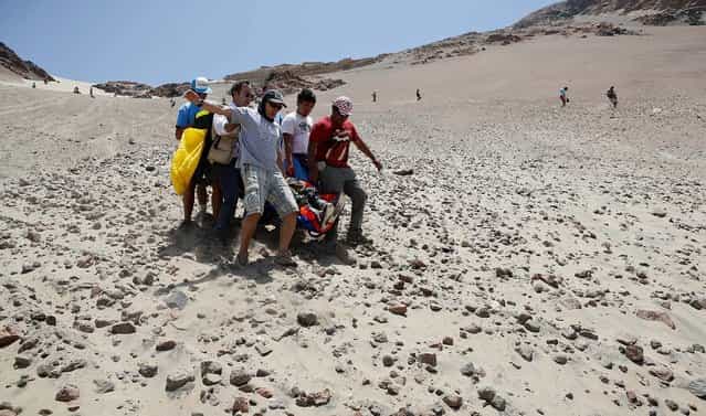 Medics, helped by fans, evacuate Leonardo Martinez of Bolivia, who was injured after crashing with his quad during the 3nd stage of the 2013 Dakar Rally. (Photo by Victor R. Caivano/Associated Press)