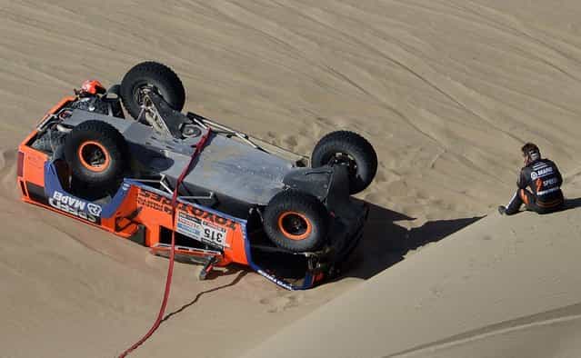 Driver Robby Gordon of the U.S. looks at his overturned Hummer during the 4th stage of the 2013 Dakar Rally. (Photo by Franck Fife/Associated Press)