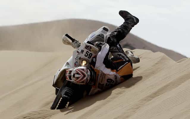 KTM rider Patrice Carillon of France falls from his motorcycle as he tries to cross a dune during the 6th stage. (Photo by Victor R. Caivano/Associated Press)