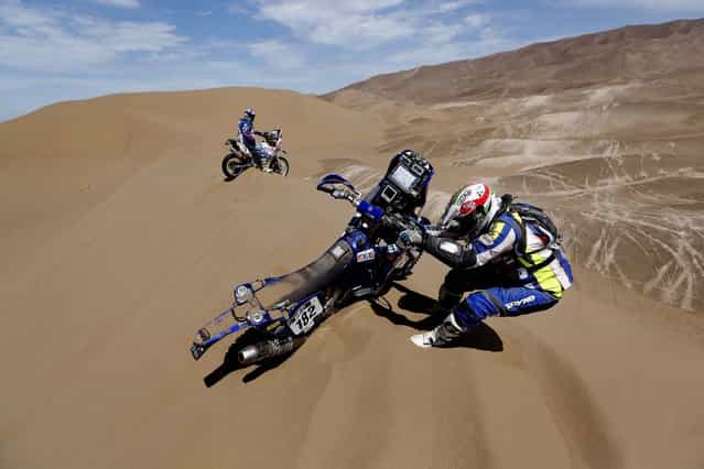Yamaha Paolo Sabbatucci of Italy, right, tries to get his motorcycle out of the sand as Yamaha teammate rider John Mckendrick of Chile waits for him during the 6th stage. (Photo by Victor R. Caivano/Associated Press)