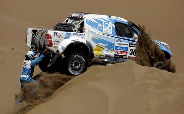 Argentine co-driver Bernardo Graue, left, and driver Lucio Alvarez, inside the vehicle, try to free their pick-up stuck on a dune during the 6th stage of the 2013 Dakar Rally. (Photo by Victor R. Caivano/Associated Press)
