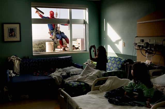 Sao Doan, 5, right, watches as her mom, Tiffany Ringer, both of Kenneth City, snaps a photo of Merrill Hunt dressed as Spiderman as he washes her window at All Children's Hospital in St. Petersburg, January 10, 2013. (Photo by Cherie Diez/The Tampa Bay Times)