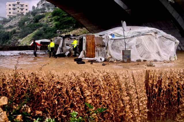 Rescue workers help a family evacuate a flooded area in Jadra, south of Beirut, Lebanon, January 7, 2013. The country has been hit with a snow storm that has blocked roads in the mountains and brought heavy rains to the capitol. (Photo by Mohammed Zaatari/Associated Press)