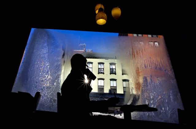 Erin Leighton sips a coffee while seated next to a frost-covered window at a coffee shop in Portland, Maine, on January 24, 2013. (Photo by Robert F. Bukaty/Associated Press)
