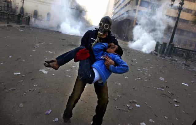 A protester evacuates an injured boy during clashes near Tahrir Square, January 25, 2013. Two years after Egypt's revolution began, the country's schism was on display Friday as the mainly liberal and secular opposition held rallies denouncing Islamist President Mohammed Morsi, saying the goals of the pro-democracy uprising have not been met. (Photo by Khalil Hamra/Associated Press)