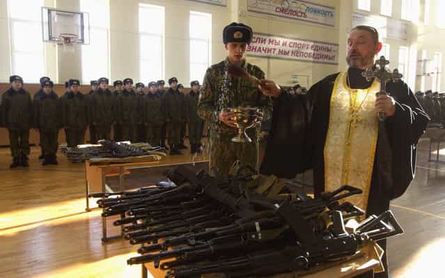 An Orthodox priest blesses rifles during a ceremony where new recruits receive their weapons at a military base of the Belarussian Interior Ministry in Minsk January 23, 2013. The traditional ceremony was attended by 325 Belarussian recruits, and it is held a month after the recruits take their military oath. (Photo by Vasily Fedosenko/Reuters)