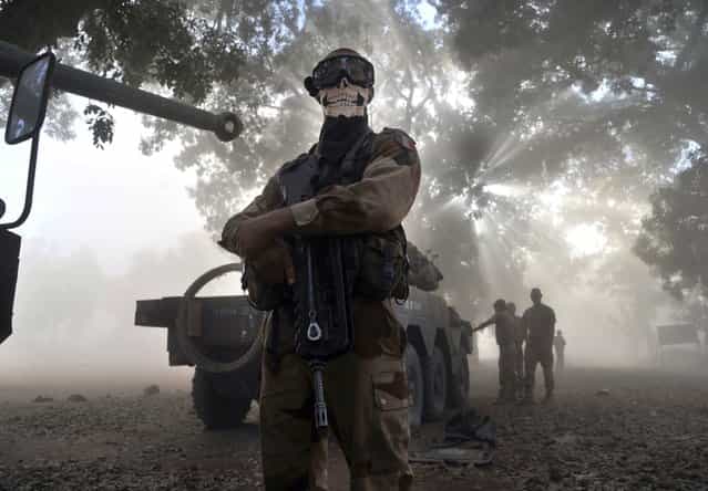 A French soldier wearing a skeleton mask stands next to a tank in a street in Niono, on January 20, 2013. French Defence Minister Jean-Yves Le Drian said today that the goal of France's military action in Mali was to retake control of the entire country from Islamist militants who have seized the north. [The goal is the total reconquest of Mali. We will not leave any pockets] of resistance, Le Drian said on French television. (Photo by Issouf Sanogo/AFP Photo)