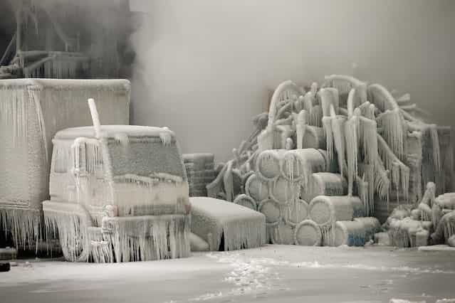 A truck is covered in ice as firefighters help to extinguish a massive blaze at a vacant warehouse on January 23, 2013 in Chicago, Illinois. More than 200 firefighters battled a five-alarm fire as temperatures were in the single digits. (Photo by Scott Olson)