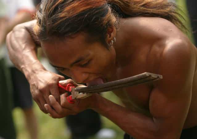 A Wa ethnic minority group entertainer licks a heated iron during a performance at the Xian Qinling Wildlife Park in Xian of Shaanxi Province, China. Xian Qinling Wildlife Park is a tourist attraction combined with animal protection, gardening, zoology science and technology, and recreations. (Photo by China Photos)