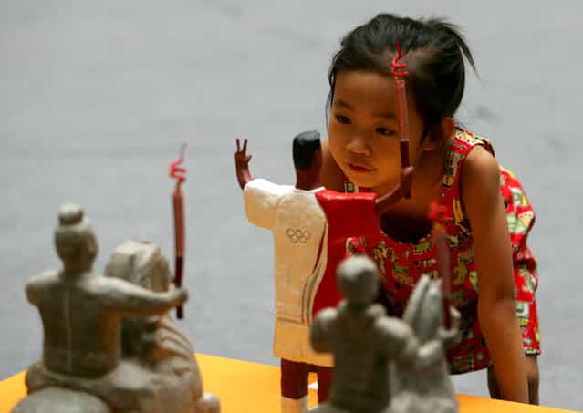 A young girl views sculpture work entitled [Prosperous Times] by artist Zhang Kaixuan is seen at an Olympic themed fine arts, calligraphy and photography exhibition at Shaanxi Art Museum in Xian of Shaanxi Province, China. (Photo by China Photos)