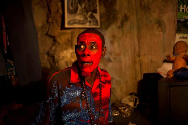 In this January 27, 2013 photo, snake handler Saintilus Resilus, with his face painted red, talks to his assistants as they get ready to perform during pre-Lenten Carnival season in Petionville, Haiti. Resilus sees himself as something of a performance artist, showing off with snakes and other animals that Haitians don't see every day, earning tips from impromptu audiences. (Photo by Dieu Nalio Chery/AP Photo/Matt Dayhoff)