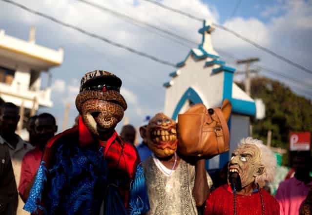 In this January 27, 2013 photo, snake handler Saintilus Resilus performs with a snake wrapped around his face as he and his assistants walk in the streets during pre-Lenten Carnival celebrations in Petionville, Haiti. Haiti's snakes aren't venomous, but they have poisoned some relationships. Resilus' wife left him in 1991. (Photo by Dieu Nalio Chery/AP Photo/Matt Dayhoff)