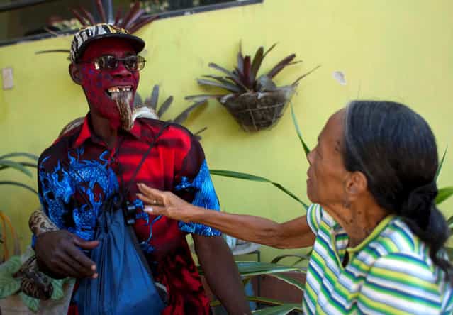 In this January 27, 2013 photo, snake handler Saintilus Resilus holds a snake with his teeth as he performs for money during the pre-Lenten Carnival season, near his home in Petionville, Haiti. Resilus has used snakes and other animals to earn a little money since at least 1974. (Photo by Dieu Nalio Chery/AP Photo/Matt Dayhoff)