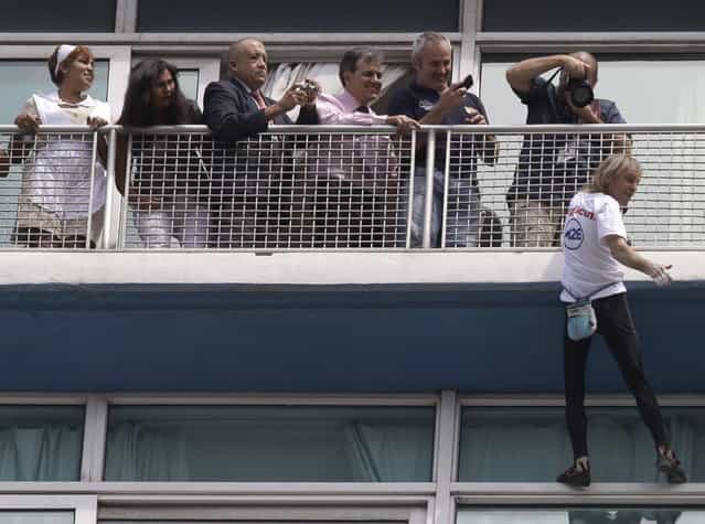 Alain Robert, holds on to a 20th floor railing as he pauses to wave to tourists and onlookers below, during his ascent to the top of the Habana Libre hotel without using ropes or a safety net, in Havana, Cuba, Monday, February 4, 2013. Once the city's Hilton, Robert was able to reach the top of the 27-story building in 30 minutes. Robert has scaled much taller buildings in his career. He says his main concern is that the hotel is in disrepair like other Havana landmarks. (AP Photo/Franklin Reyes)