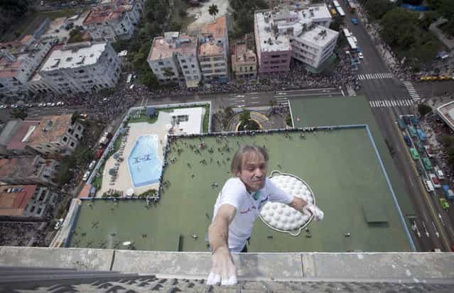 Curious tourists and locals watch from below as French daredevil Alain Robert scales the Habana Libre hotel without using ropes or a safety net, in Havana, Cuba, Monday, February 4, 2013. Once the city's Hilton, Robert was able to reach the top of the 27-story building in 30 minutes. Robert has scaled much taller buildings in his career. He says his main concern is that the hotel is in disrepair like other Havana landmarks. (AP Photo/Ramon Espinosa, Pool)