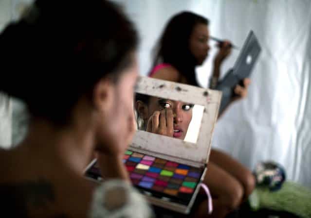 Samba dancer Diana Prado applies makeup before the start of a carnival parade at central station in Rio de Janeiro. Prado made her Carnival debut at age 19, after auditioning for a spot with the Sao Clemente, one of 13 top-tier schools that will compete for the annual titles at Rio's Sambadrome this weekend. (Photo by Felipe Dana/Associated Press)