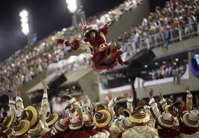 A performer from the Sao Clemente samba school is tossed in the air during carnival celebrations at the Sambadrome in Rio de Janeiro, Brazil, Tuesday, February 12, 2013. (Photo by Silvia Izquierdo/AP Photo)
