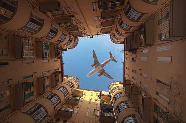 This photo taken in Naples, Italy is of a plane flying over a building with the photo taken at the perfect time while the plane is passing over an open area of the building, creating the Perfect Shot. The photo is actually not one single photo, but two photos combined together. One image is of the top part of the building and the plane flying over. A second image had to be combined for the lower portion of the building since the original photo’s lighting of the bottom portion was bad quality, so two images were superimposed together. (Photo by Iryna)