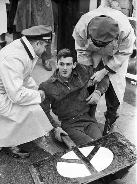 In this January 12, 1963 file photo, demonstrator Michael Kirby, 25, of Milton, Mass., carrying a peace sign, is taken into custody by police in Groton, Conn., outside the launching site of the Polaris nuclear missile submarine USS Nathan Hale. Kirby, a former nuclear weapons specialist in the Navy, was one two pacifists arrested at the site. (Photo by AFP Photo)