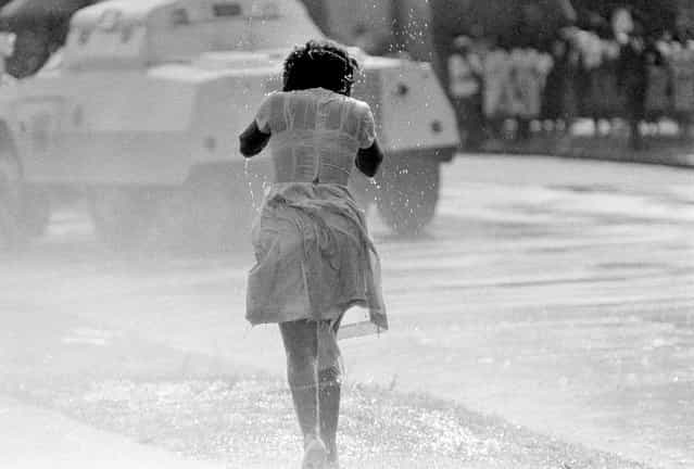 A young black woman, soaked by a fireman's hose as an anti-segregation march is broken up by police, in Birmingham, Alabama, on May 8, 1963. In the background is a police riot wagon. (Photo by AP Photo)