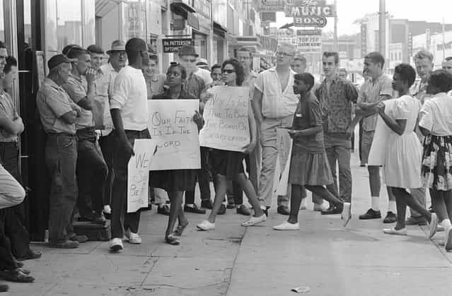 A picketer in front of a Gadsden, Alabama, drugstore turns to answer a heckler during a demonstration, on June 10, 1963. About two dozen black youths picketed several stores and two theaters. There were no arrests and no violence. (Photo by AP Photo)