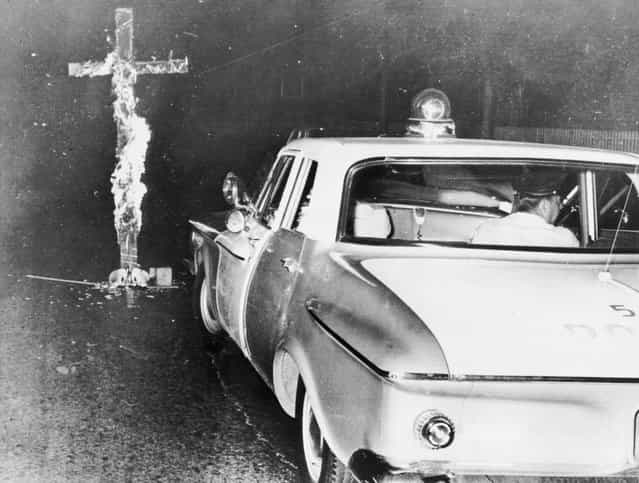 Chicago police move in to knock down a burning cross in front of a home, after an African-American family moved into a previously all white neighborhood, on the 6th consecutive night of disturbances, on August 3, 1963. (Photo by Library of Congress)