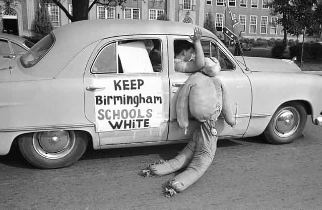 White students in Birmingham, Alabama, drag an African American effigy past West End High School, on September 12, 1963. Two African American girls attended the desegregated school and a majority of the white students were staying away from classes. Police stopped this car in a segregationist caravan in front of the school to caution them about fast driving and blowing auto horns in front of a school. (Photo by AP Photo)