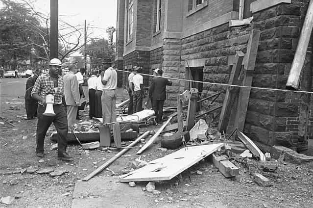 A civil defense worker and firemen walk through debris from an explosion which struck the 16th street Baptist Church, killing four girls and injuring 22 others, in Birmingham, Alabama, on September 15, 1963. The open doorway at right is where the girls are believed to have died. The horrific attack rallied public support to the cause of civil rights. Four men, members a Ku Klux Klan group, were responsible for planting a box of dynamite under the steps of the church. Three of the four were eventually tried and convicted. (Photo by AP Photo)