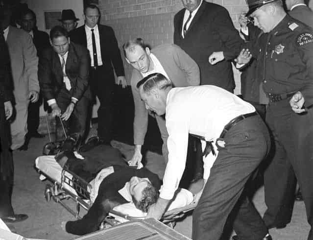 Lee Harvey Oswald, accused assassin of President John F. Kennedy, is placed on a stretcher after moments after being shot in the stomach in Dallas, Texas, on November 24, 1963. Nightclub owner Jack Ruby shot and killed Oswald as the prisoner was being transferred through the underground garage of Dallas police headquarters. (Photo by AP Photo)