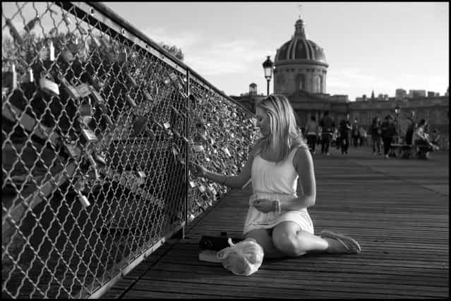 The Bridge of Love-Le Pont Des Arts, Paris. Every lock on this bridge represents a story, each one different and while sometimes similar, always unique. I came across Jodie yesterday evening, a young woman from Australia beginning a many month trip around the world. She seemed deep in thought as she held onto a lock on the bridge and only moments later she through the key over the rail into the Seine. Before she got up to leave, she turned to me and told me that she had placed a lock on the bridge for her and her boyfriend Alexander who she wouldn't see for a long time before returning home. This moment made me think for a second about how much we take for granted in this digital age the immediacy of communication-and it made me think of my own young adult life when we still wrote letters and posted them and waited for one to return. It made me think of my great, great grandfather who left Scotland to go and work a team of horses taking men to mine gold in Australia in the mid 1800's, before returning to marry the daughter of the aristocrat he worked for back in Scotland, and their eventual move to America when he was shunned by her family for being a commoner. LIfe is made of up of stories, and photographs, like locks on a bridge, represent a symbol of how they live on. (Photo and comment by Peter Turnley)