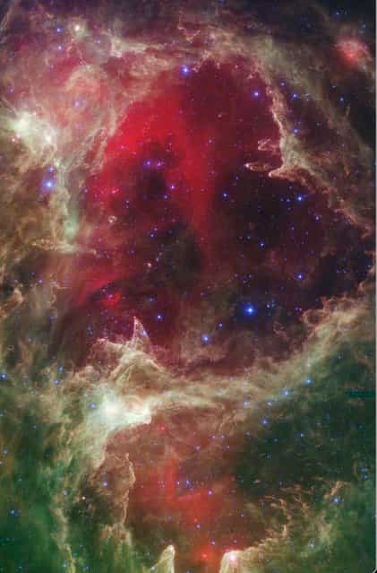 An infrared portrait from NASA's Spitzer Space Telescope which shows generations of stars is seen in this undated NASA handout image released February 14, 2013. In this wispy star-forming region, called W5, the oldest stars can be seen as blue dots in the centers of the two hollow cavities (other blue dots are background and foreground stars not associated with the region). Red shows heated dust that pervades the region's cavities, while green highlights dense clouds. (Photo by NASA/Reuters/JPL-Caltech/Harvard-Smithsonian/Handout)