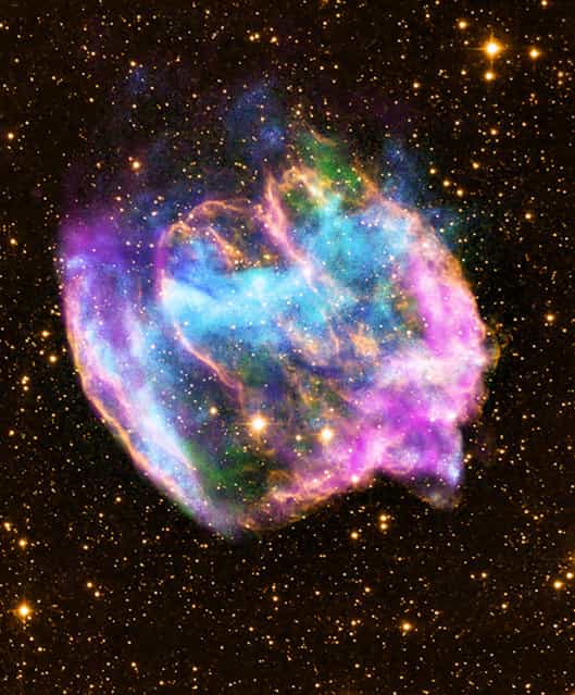 This NASA Chandra X-Ray Observatory image shows a highly distorted supernova remnant that may contain the most recent black hole formed in the Milky Way galaxy. The composite image combines X-rays from Chandra (blue and green), radio data from the Very Large Array (pink), and infrared data from the Palomar Observatory (yellow). Most supernova explosions that destroy massive stars are generally symmetrical. In the W49B supernova, however, it appears that the material near its poles was ejected at much higher speeds than that at its equator. There is also evidence that the explosion that produced W49B left behind a black hole and not a neutron star like most other supernovas. (Photo by L. Lopez/MIT/CXC/NASA via AFP Photo)