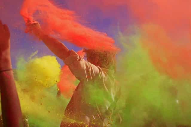People throw paint powder in the air during the holi one colour Festival held in the city of Cape Town, South Africa, Saturday, March 2, 2013. Thousands of people are taking part in the festival by throwing coloured paint powder at each other to express freedom and the colour of everyday life. (Photo by Schalk van Zuydam/AP Photo)