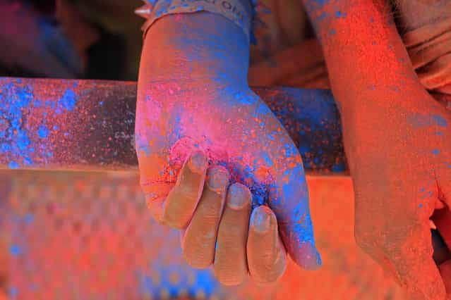 A woman hands inside a cloud of paint powder next to her friend's during the holi one colour Festival held in the city of Cape Town, South Africa, Saturday, March 2, 2013. Thousands of people took part in the festival by throwing coloured paint powder at each other to express freedom and the colour of everyday life. (Photo by Schalk van Zuydam/AP Photo)